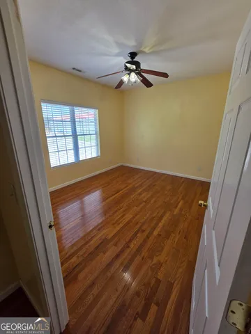 a view of a room with wooden floor ceiling fan and window