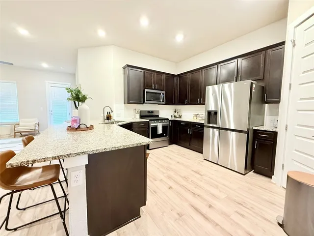 a kitchen with granite countertop a refrigerator and a stove top oven