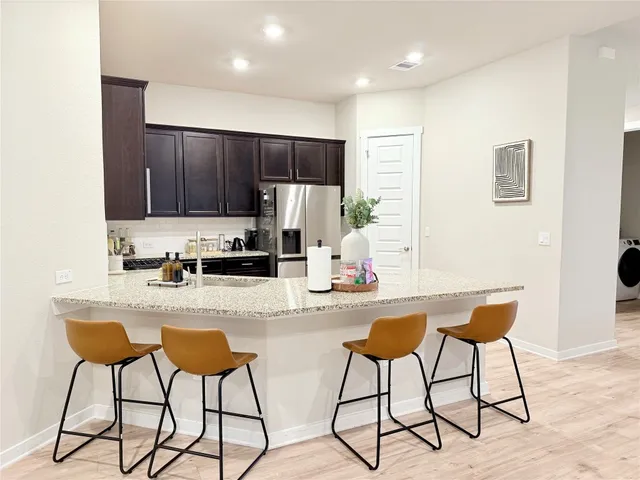 a kitchen with stainless steel appliances kitchen island granite countertop a refrigerator and cabinets