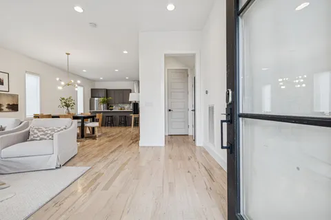 a view of a living room kitchen with stainless steel appliances kitchen island granite countertop wooden floor view and a window