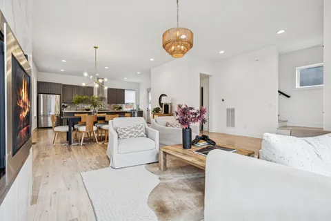 a living room with furniture kitchen view and a chandelier