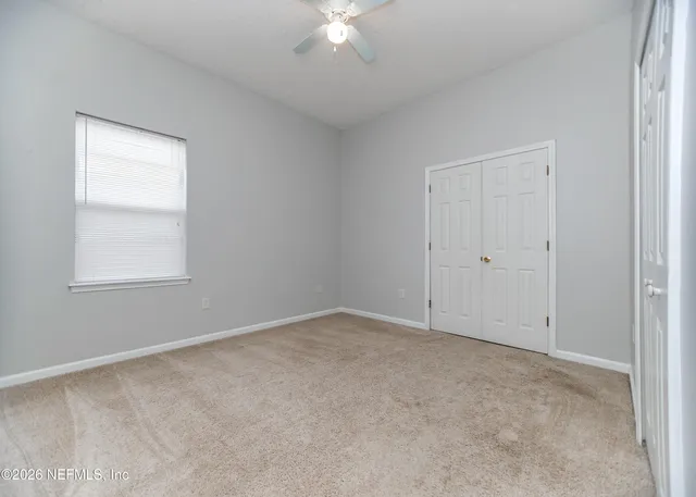 an empty room with a ceiling fan and a window