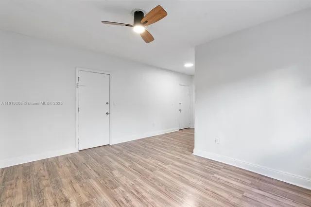 an empty room with wooden floor ceiling fan and window
