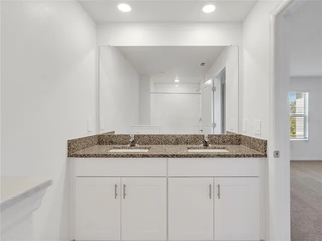 a bathroom with a granite countertop sink and a mirror