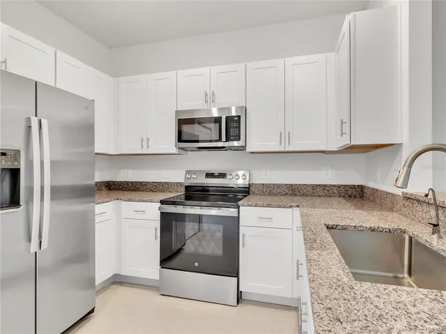 a kitchen with stainless steel appliances granite countertop a stove a microwave and a refrigerator