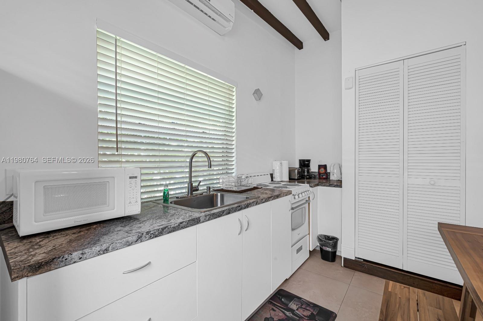1044 Southwest 13th Court, Unit 2 Miami, FL 33135 - Photo 13 of 17 a kitchen with stainless steel appliances granite countertop a sink and a white wooden cabinets