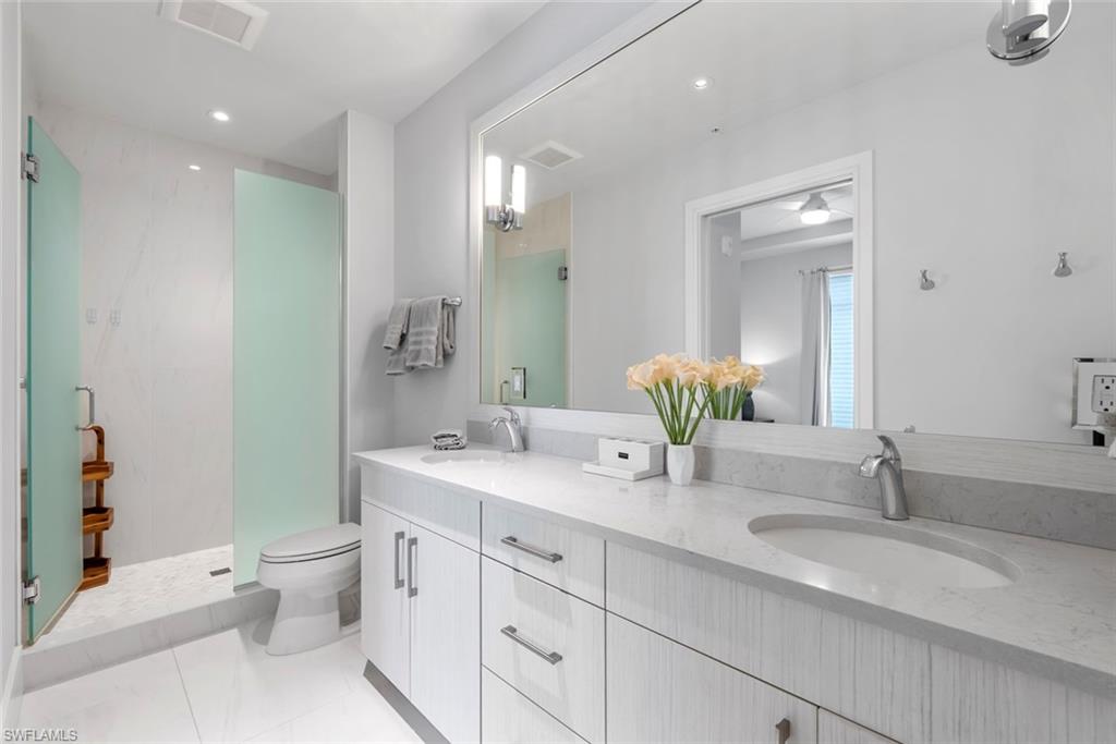 101 8th Street South, Unit 201 Naples, FL 34102 - Photo 11 of 21 a bathroom with a double vanity sink toilet and a mirror