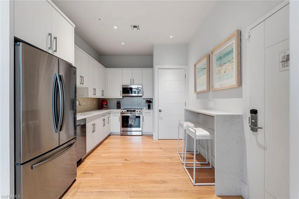 101 8th Street South, Unit 201 Naples, FL 34102 - Photo 5 of 21 a kitchen with granite countertop a refrigerator and a stove top oven
