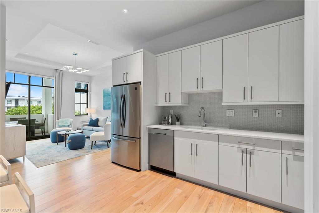 101 8th Street South, Unit 201 Naples, FL 34102 - Photo 7 of 21 a kitchen with white cabinets and stainless steel appliances