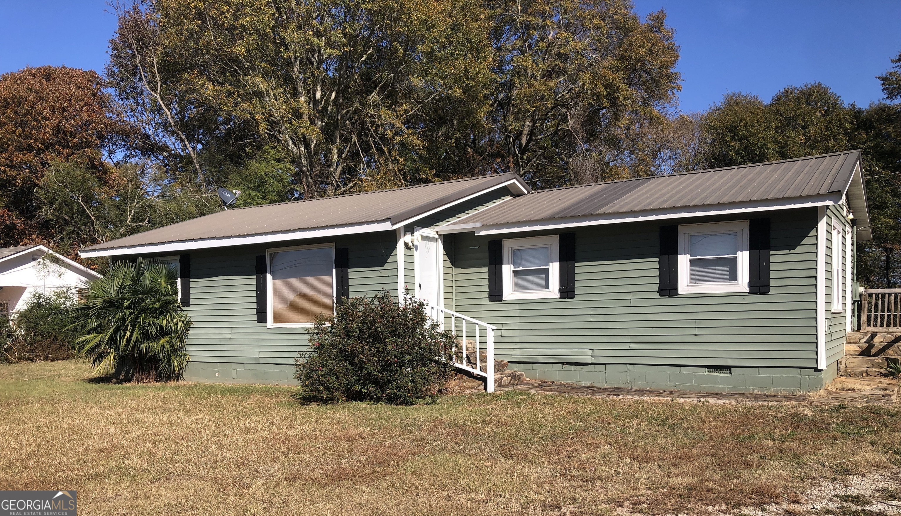 a side view of house with yard and trees in the background