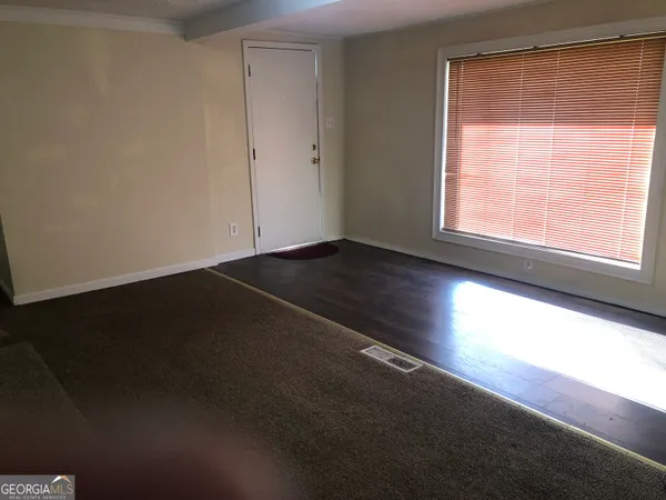 a view of an empty room with wooden floor and a window