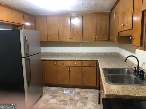 a kitchen with stainless steel appliances granite countertop a refrigerator a sink and a stove