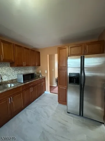 a large kitchen with granite countertop a refrigerator and cabinets