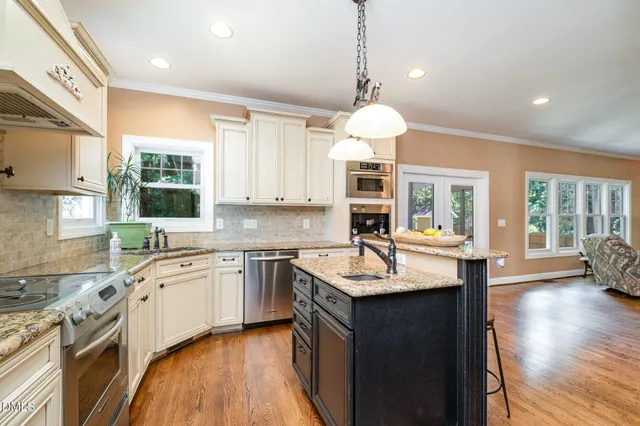a kitchen with stainless steel appliances granite countertop a sink a stove and a wooden floors
