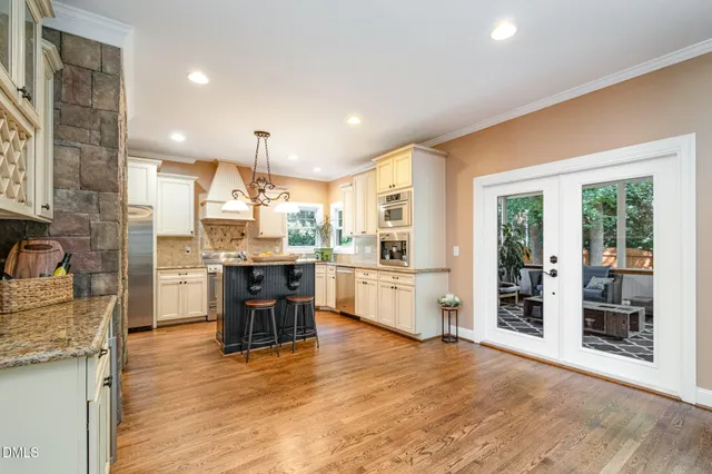 a kitchen with stainless steel appliances kitchen island granite countertop a refrigerator a sink a stove and oven with wooden floor