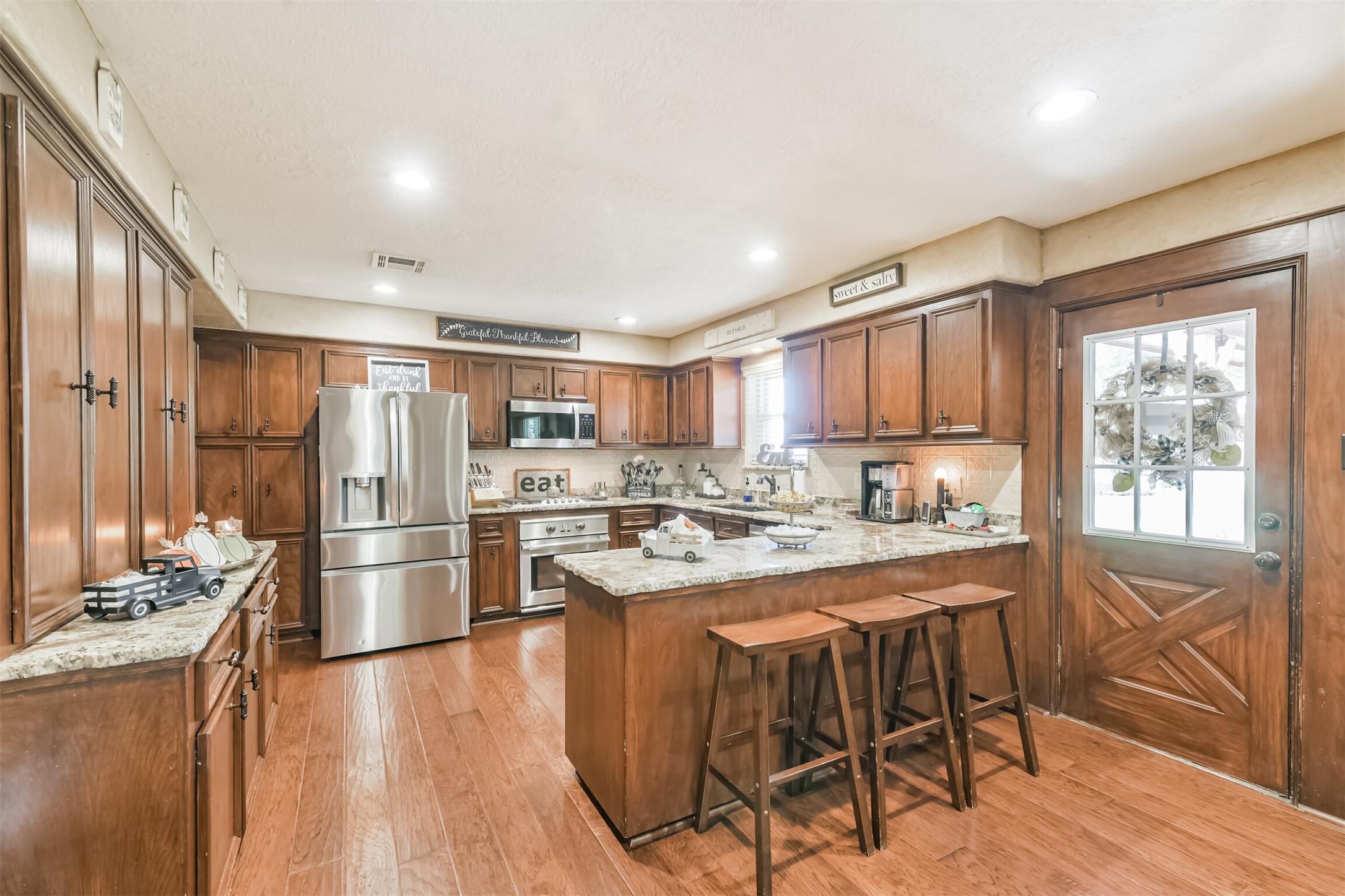 307 West Hufsmith Road Tomball, TX 77375 - Photo 15 of 44 Charming kitchen with rich wooden cabinetry, sleek stainless steel appliances, and a spacious granite island with seating, perfect for entertaining.