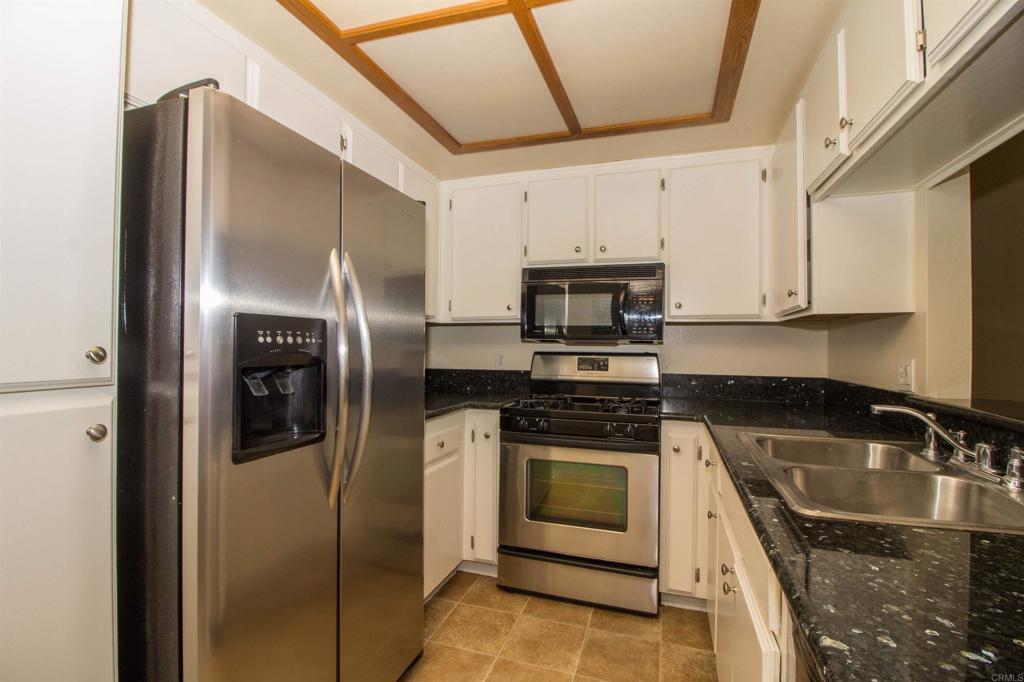 2023 Lakeridge Circle, Unit 203 Chula Vista, CA 91913 - Photo 8 of 24 a kitchen with stainless steel appliances granite countertop a refrigerator a stove and a sink with wooden floor