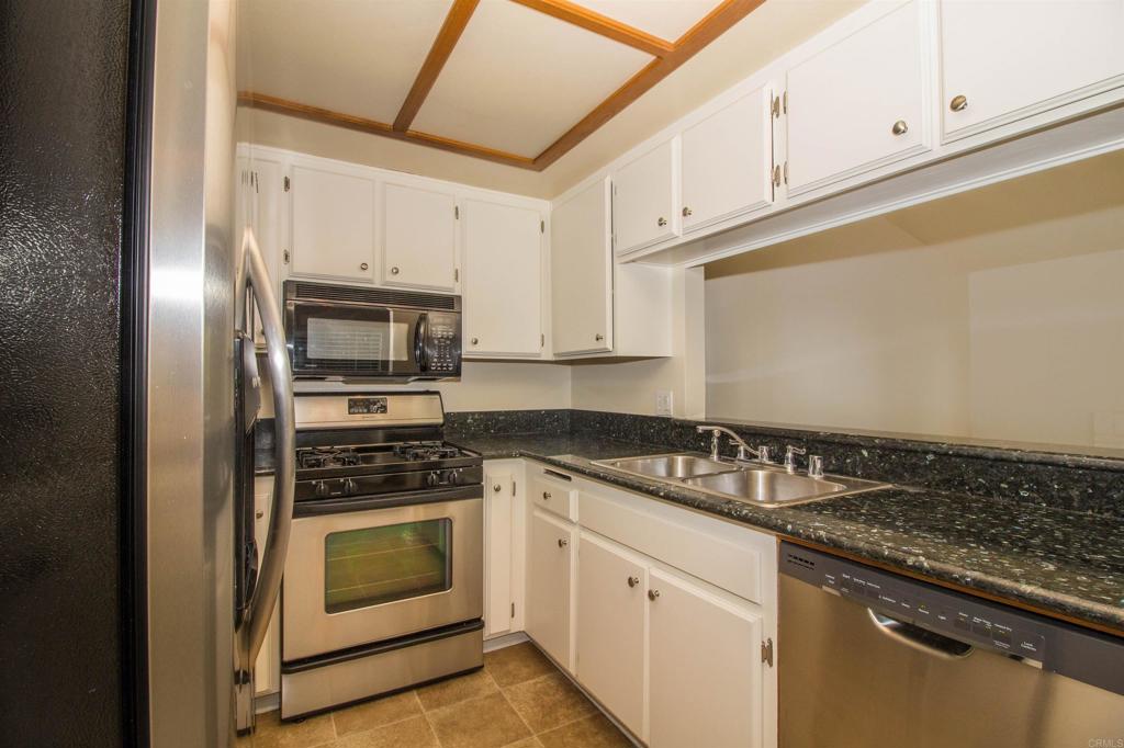 2023 Lakeridge Circle, Unit 203 Chula Vista, CA 91913 - Photo 9 of 24 a kitchen with granite countertop white cabinets and stainless steel appliances