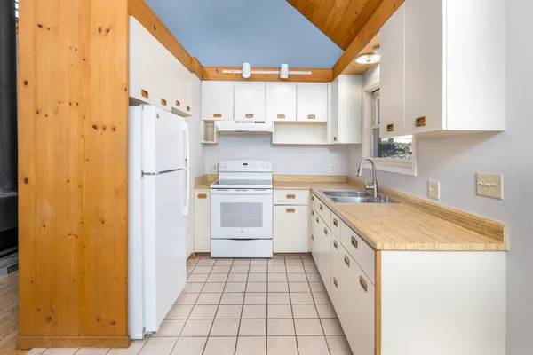 a kitchen with a sink a refrigerator a window and cabinets