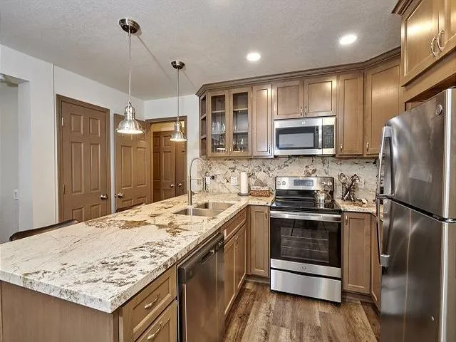 a kitchen with granite countertop a refrigerator a sink a stove a microwave and island