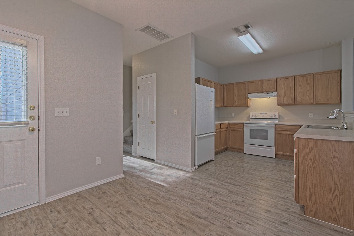 1102 East 3rd Street Georgetown, TX 78626 - Photo 10 of 36 Kitchen with light countertops, white appliances, light wood-style floors, and under cabinet range hood