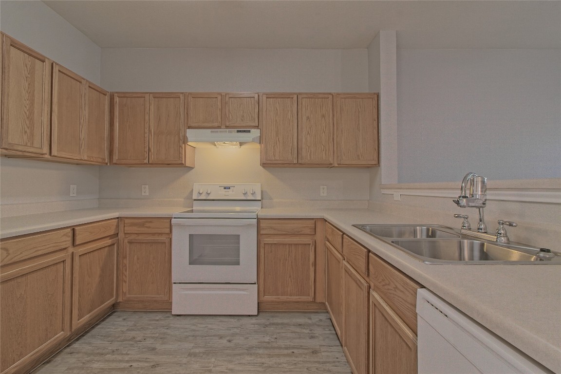 1102 East 3rd Street Georgetown, TX 78626 - Photo 11 of 36 Kitchen with white appliances, light countertops, under cabinet range hood, and light wood-style flooring