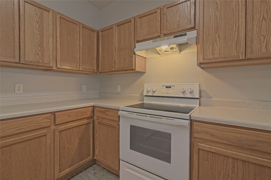 1102 East 3rd Street Georgetown, TX 78626 - Photo 13 of 36 Kitchen with white electric range oven, under cabinet range hood, and light countertops