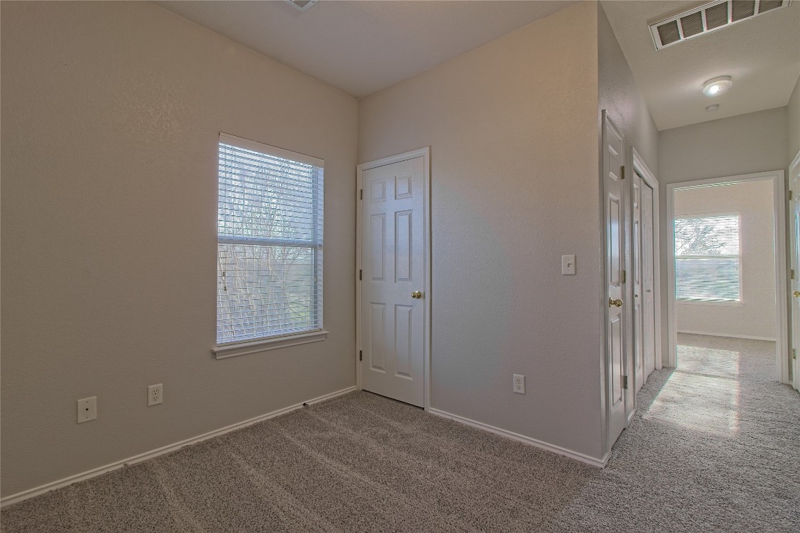 1102 East 3rd Street Georgetown, TX 78626 - Photo 19 of 36 Unfurnished bedroom with light carpet, multiple windows, and a closet
