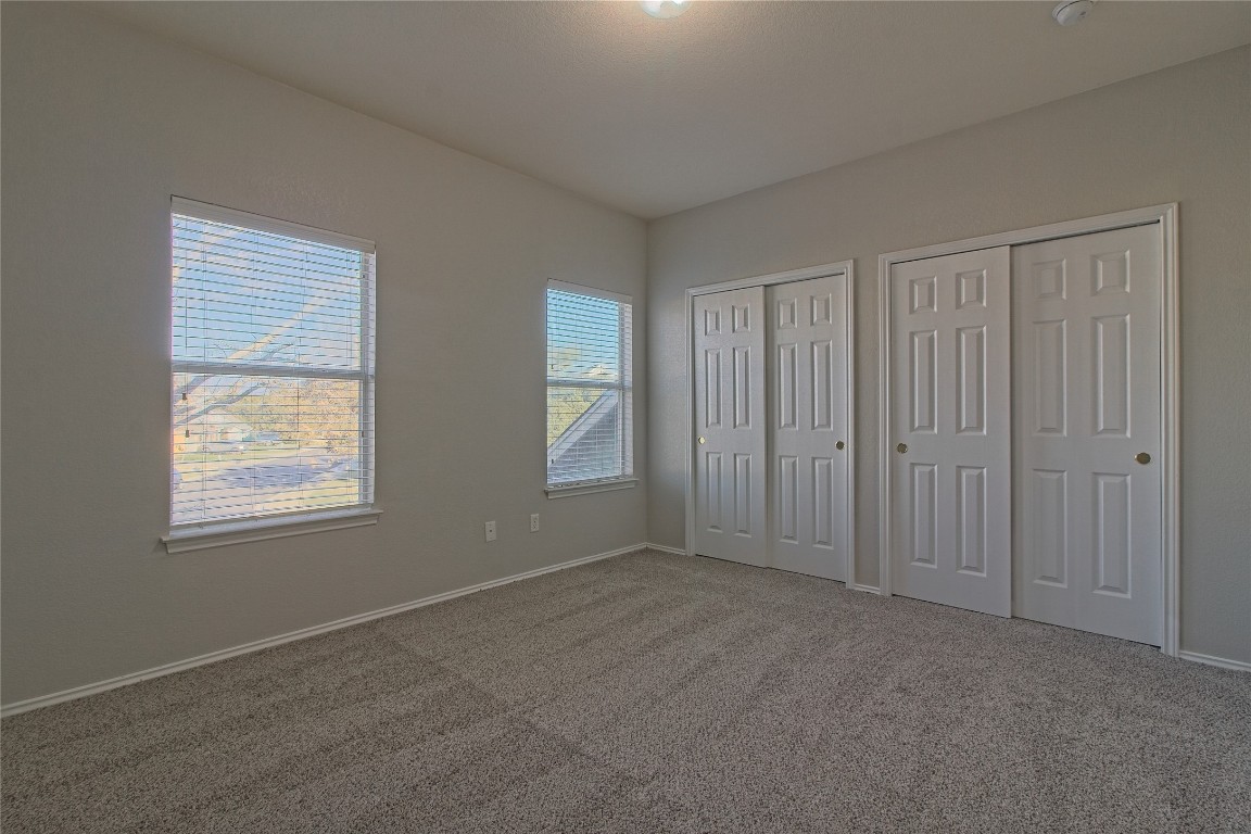 1102 East 3rd Street Georgetown, TX 78626 - Photo 20 of 36 Unfurnished bedroom with multiple closets and carpet flooring