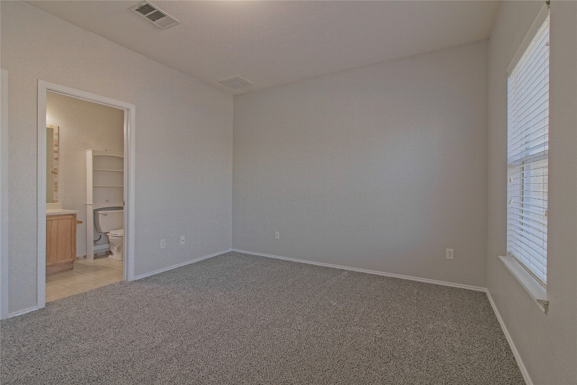 1102 East 3rd Street Georgetown, TX 78626 - Photo 21 of 36 Unfurnished bedroom with light colored carpet and connected bathroom