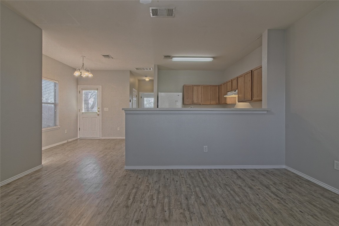 1102 East 3rd Street Georgetown, TX 78626 - Photo 7 of 36 Kitchen with a chandelier, brown cabinets, light wood-type flooring, and pendant lighting
