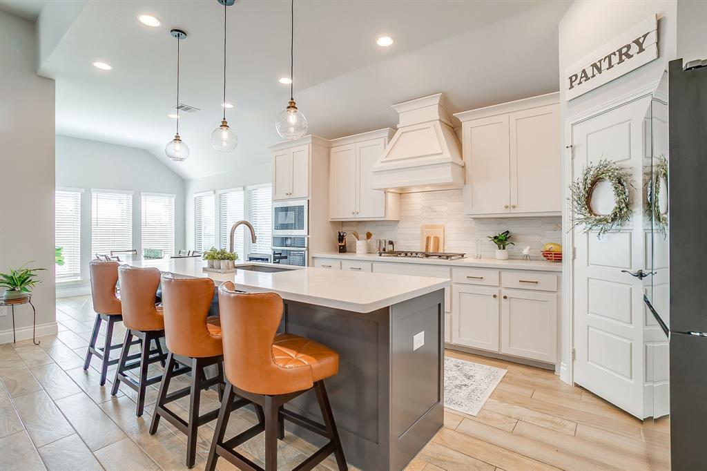 2453 Lazy Dog Lane Northlake, TX 76247 - Photo 13 of 40 Kitchen with backsplash, a breakfast bar area, recessed lighting, hanging light fixtures, and white cabinets