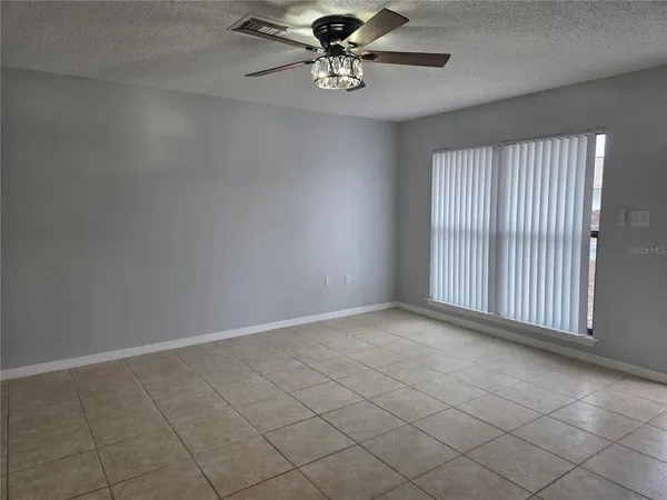 en empty room with windows and ceiling fan