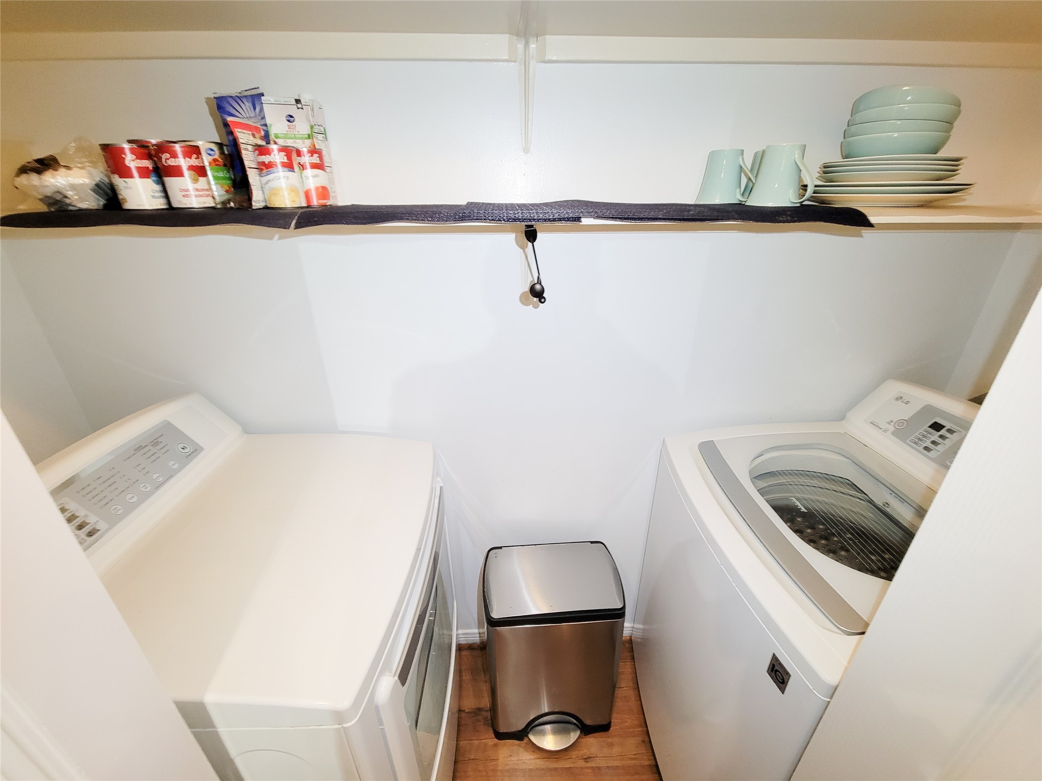 3525 Sage Road, Unit 1605 Houston, TX 77056 - Photo 11 of 33 Compact laundry closet featuring a side-by-side washer and dryer with overhead shelving for storage, well-organized and clean.