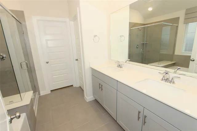 a spacious bathroom with a double vanity sink a mirror and a shower