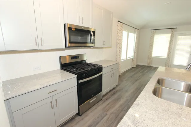 a kitchen with granite countertop white cabinets and black appliances