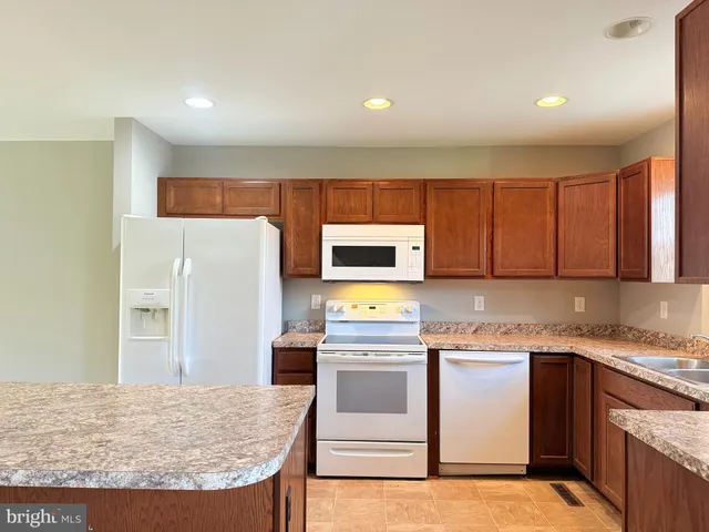 a kitchen with stainless steel appliances granite countertop a stove a refrigerator a sink and white cabinets