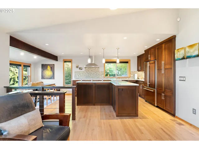 a kitchen with stainless steel appliances granite countertop a refrigerator a sink a stove and wooden cabinets