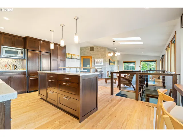 a kitchen with stainless steel appliances kitchen island granite countertop a table chairs and a view of living room