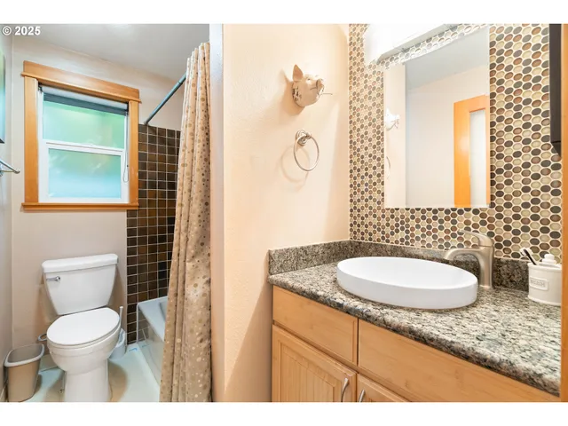 a bathroom with a granite countertop sink toilet and mirror