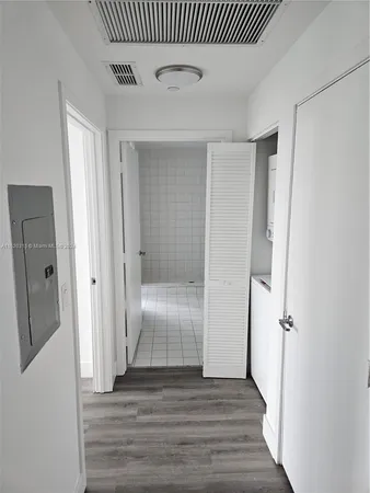 an empty room with wooden floor and a hallway