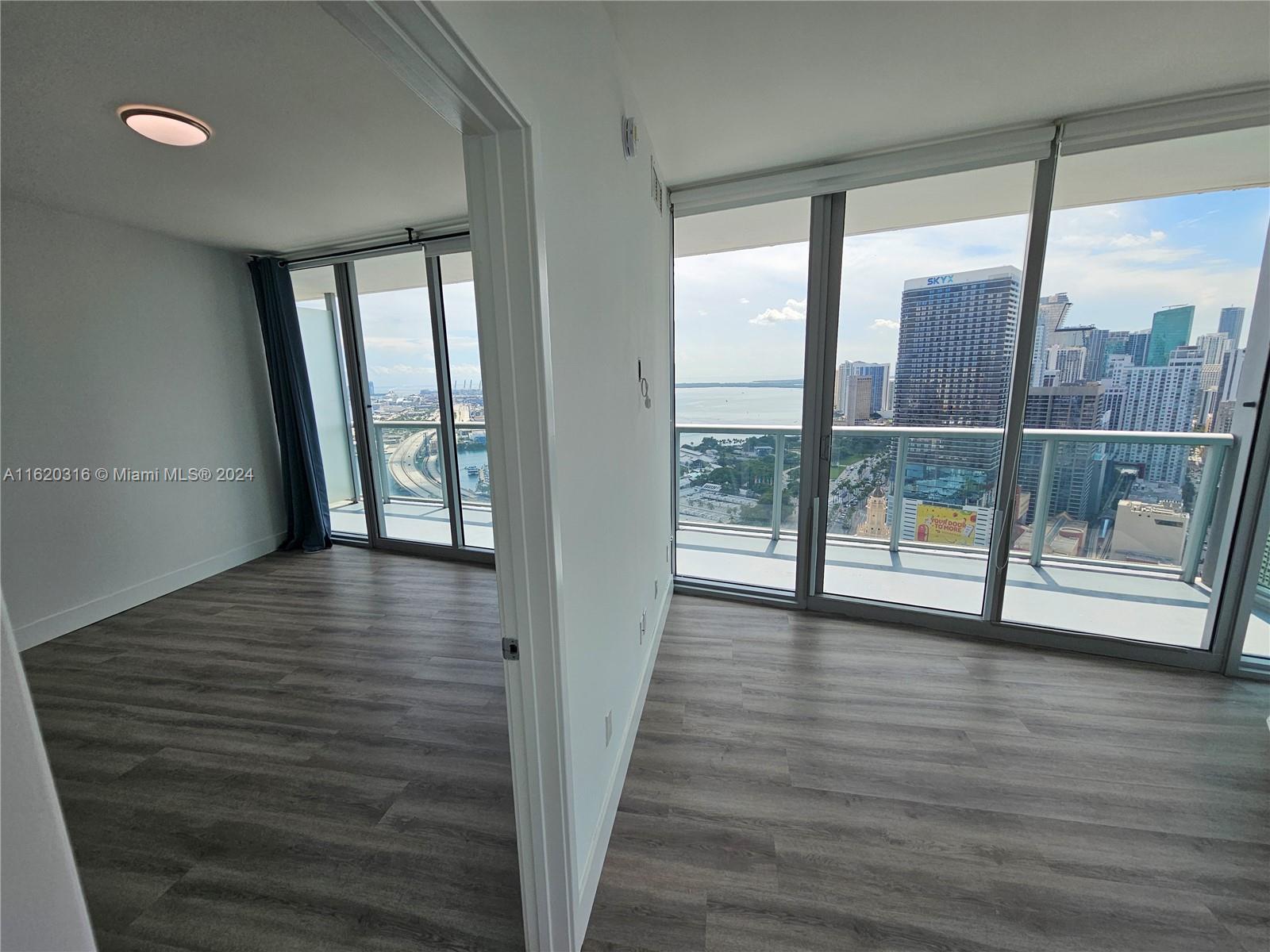 888 Biscayne Boulevard, Unit 2701 Miami, FL 33132 - Photo 5 of 37 a view of wooden floor and windows in a room