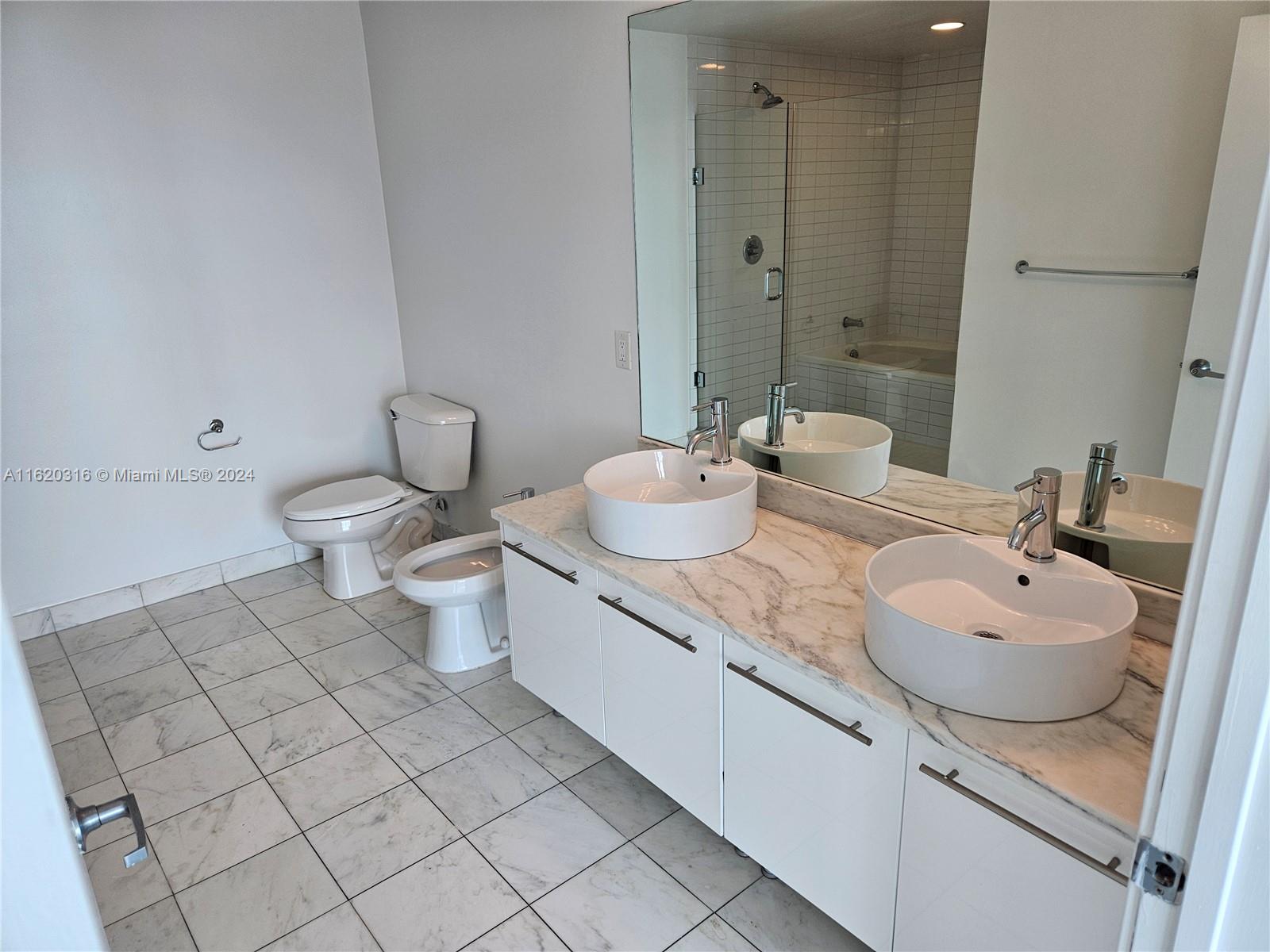 888 Biscayne Boulevard, Unit 2701 Miami, FL 33132 - Photo 10 of 37 a bathroom with a double vanity sink toilet and mirror