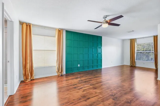 a view of empty room with wooden floor and fan