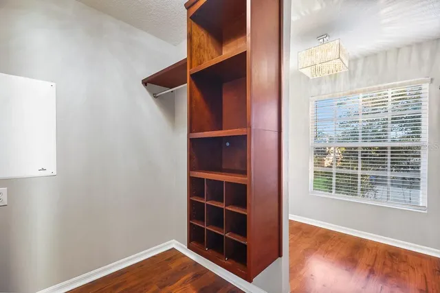 a view of an empty room with wooden floor and cabinet