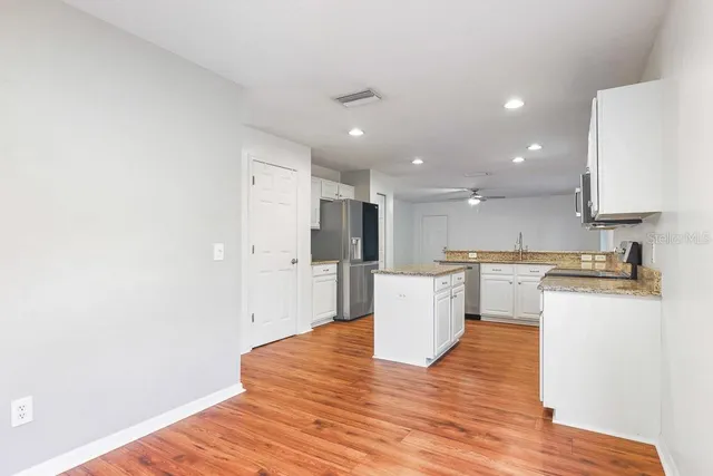 a kitchen with stainless steel appliances granite countertop a stove top oven a sink dishwasher and a microwave oven on the wooden floor