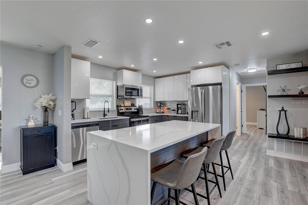 8201 Ridge Road Seminole, FL 33772 - Photo 4 of 36 a kitchen with stainless steel appliances a refrigerator a stove a sink a dining table and chairs