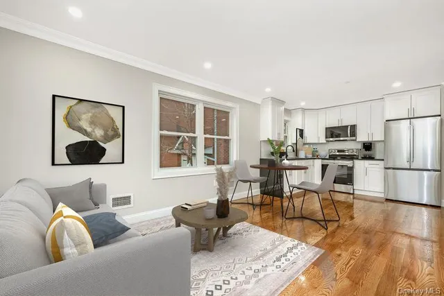 a kitchen with granite countertop a refrigerator stove a sink and white cabinets with wooden floor