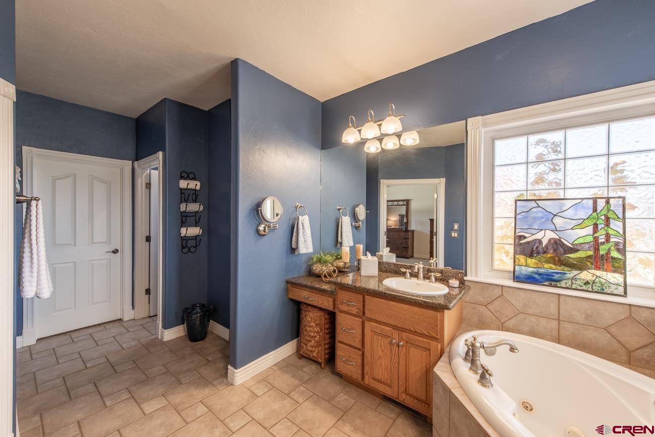 68020 Tumbleweed Road Montrose, CO 81403 - Photo 14 of 45 a bathroom with a bathtub a sink and a large mirror