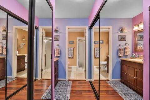 a view of a hallway with bathroom and wooden floor